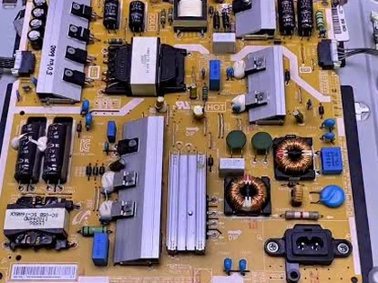 TV power supply board being tested with a multimeter
